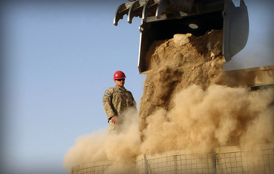 A Soldier assigned to the 1191st Engineer Company supervises the dirt extraction of Hesco barriers.