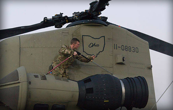 An Ohio National Guard Soldier deployed in support of U.S. Forces Afghanistan inspects and washes a CH-47 Chinook helicopter.