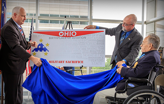 State Rep. Terry Johnson (from left), Ohio Bureau of Motor Vehicles Registrar Donald J. Petit and Medal of Honor recipient Ron Rosser unveil the design for the new Military Sacrifice specialty license plate.