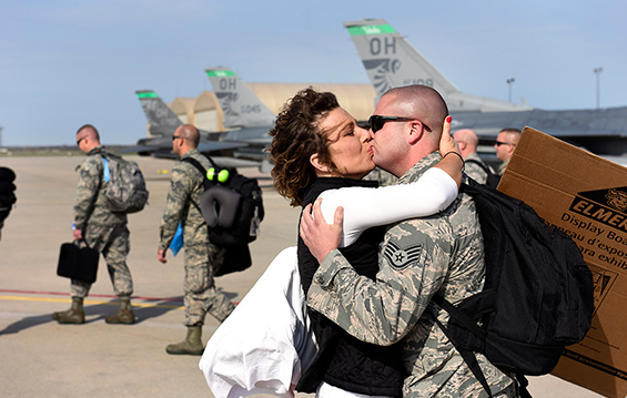 Staff Sgt. Adam Hill (right) kisses his fiancé, Lindsay Miller, after she accepted his proposal on the flight line at the 180th Fighter Wing, during a homecoming reception.
