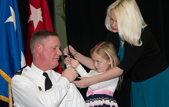 Karen Stivers helps her daughter Sarah affix new shoulder boards on the uniform of her father, Brig. Gen. Steven E. Stivers.
