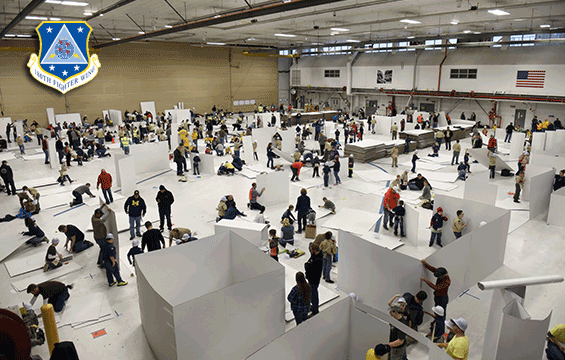 Balcony shot of scouts creating things from large cardboard boxes in air hangar.