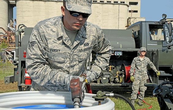 Senior Airman John Ramsey VI (left) loads fuel into a barrel to power a generator as Staff Sgt. Levi Wiskirchen regulates the flow of diesel fuel.