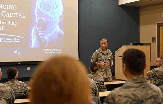 Col. Richard Tatem stands in front of classroom presenting the Enhancing Human Capital (EHC) course to class of airmen.