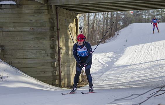Capt. Lauren Weber skiing downhill through wooden underpass.