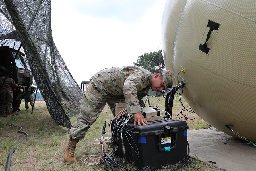 Soldier looks over generator in field.