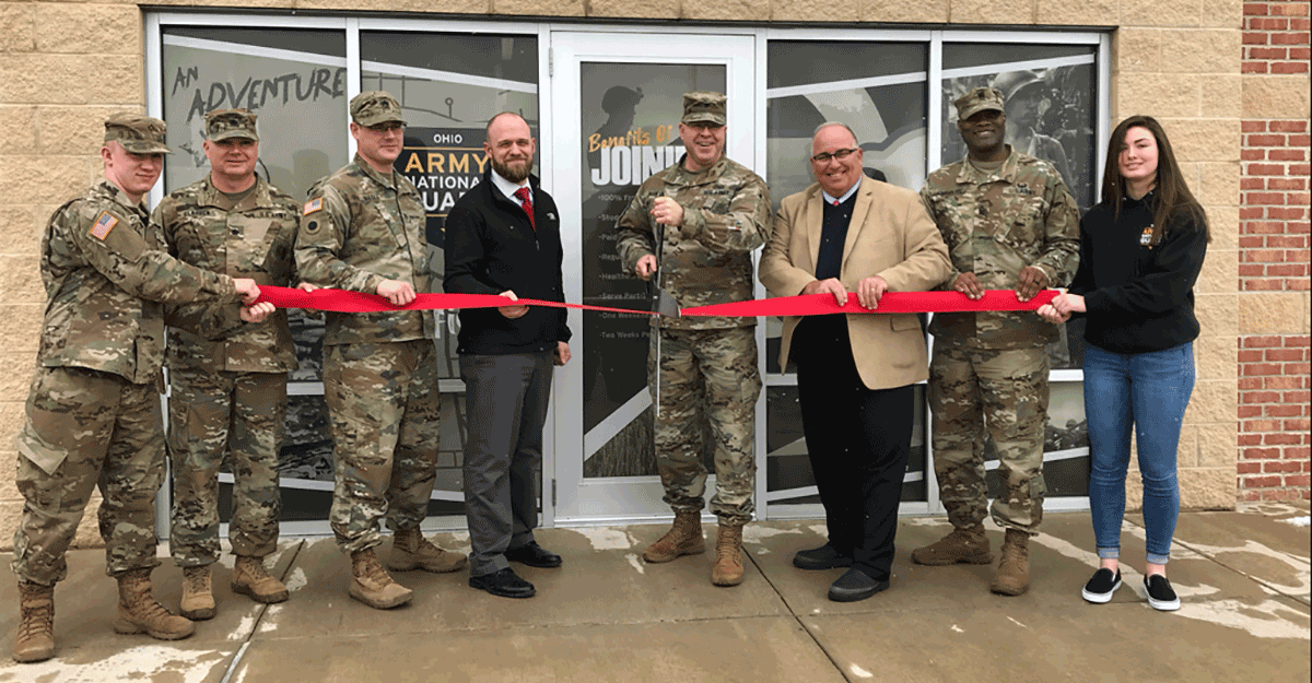 Soldiers, leaders, and officials with ribbon in front of doors to recruiting office