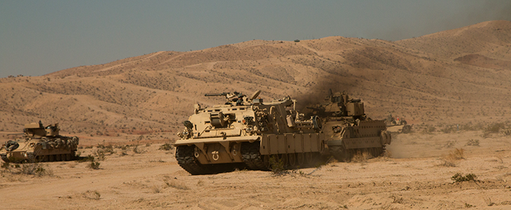 An M88 Hercules recovery vehicle tows an M3 Bradley Cavalry Fighting Vehicle from the battlefield during simulated combat operations.