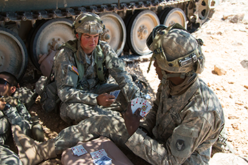 Soldiers with the 1st Battalion, 145th Armored Regiment play a hand of cards during down time between simulated combat operations missions.