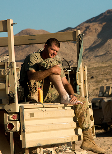 A Soldier checks his feet and applies powder in between simulated combat operations.