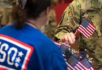 A Soldier with the 371st Sustainment Brigade receives a small American flag from a USO volunteer.