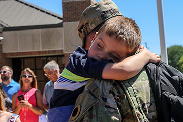 A young boy holds his father tightly.