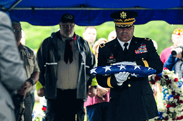 Maj. Gen. John C. Harris Jr., Ohio assistant adjutant general for Army, carries a folded American flag during graveside services for Technician 4th Grade John Kovach Jr.