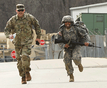 Spc. Myeeah Scott (right), representing the 16th Engineer Brigade, sprints across the finish line of an 8-mile ruck march.