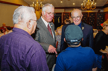 Retired Command Sgt. Maj. Rodney Newell (second from left) and retired Brig. Gen. Lance Tallmadge (right) talk with fellow alumni.