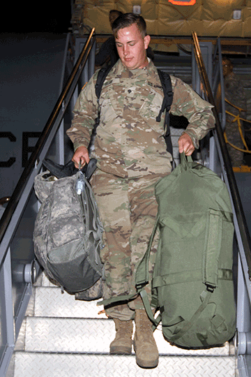 Spc. Steven Guay, a signal support system specialist attached to the 137th Signal Company, disembarks from a KC-135 Stratotanker.