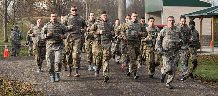 Group of 25 plus soldiers running on gravel road in the fall.
