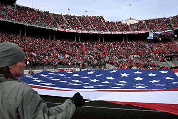Ohio National Guard Soldiers and Airmen hold a giant U.S. flag on the field at Ohio Stadium.