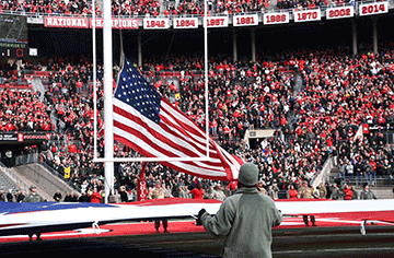 Ohio National Guard Soldiers and Airmen hold a giant U.S. flag on the field at Ohio Stadium.