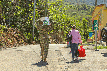 Capt. David Kirker carries water and a case of food to a Puerto Rican citizen’s house.