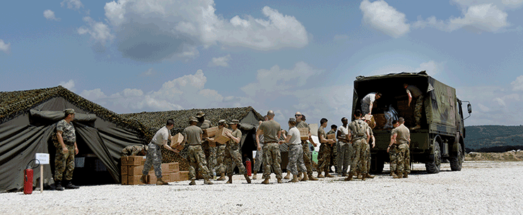 Assembly line of soldiers loading trucks from tents.