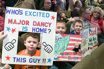 Boys hold signs as they wait for their Dad.