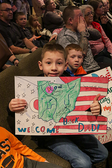 Boy holds sign as he waits for his Dad.