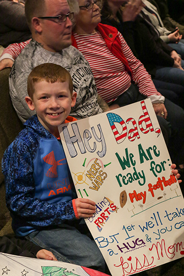 Boy holds sign as he waits for his Dad.