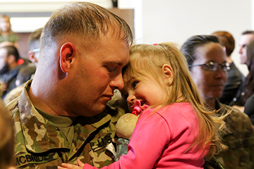 Soldier holds little girl.