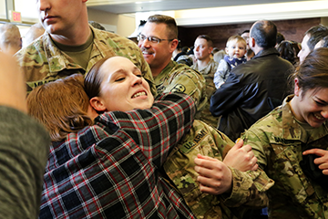 Female soldier getting hug from loved one.