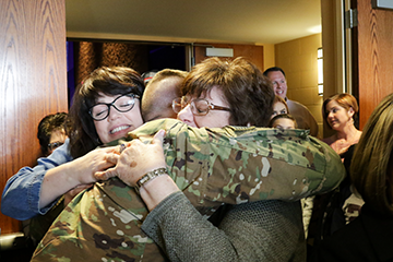 Soldier getting hugs from loved ones.