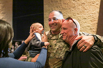Soldier poses for photo with infant and family.