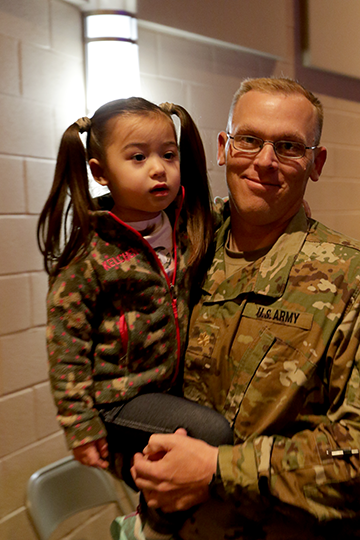 Soldier holds young girl.