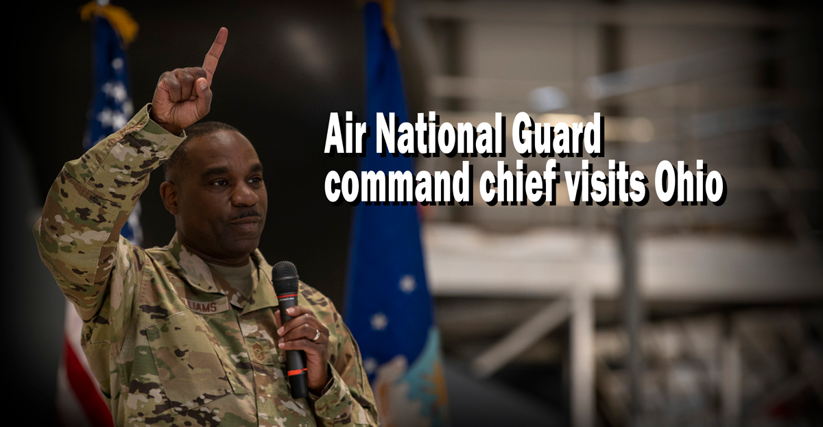 African-American Air commander raises #1 sign while holding microphone.
