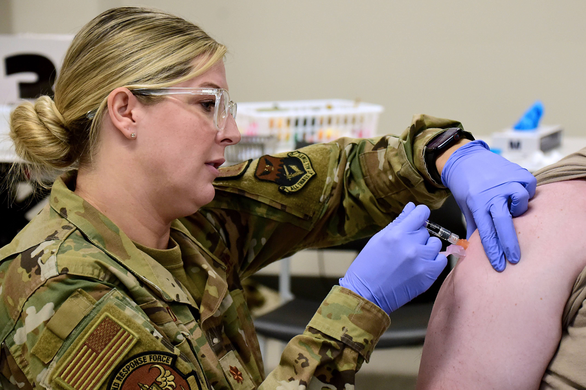 Female airman gives giving a shot into patient's arm