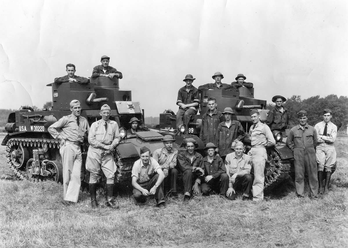 Soldiers pose on tanks.