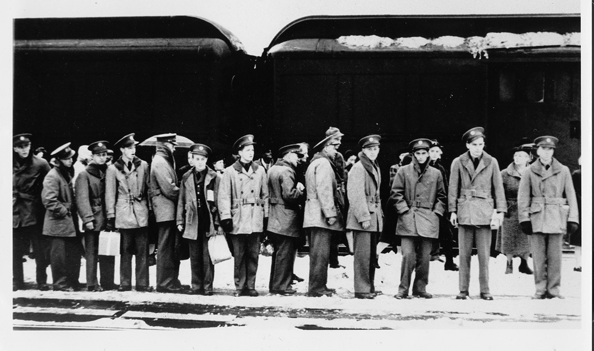 Soldiers standing in snow waiting to load onto the train.