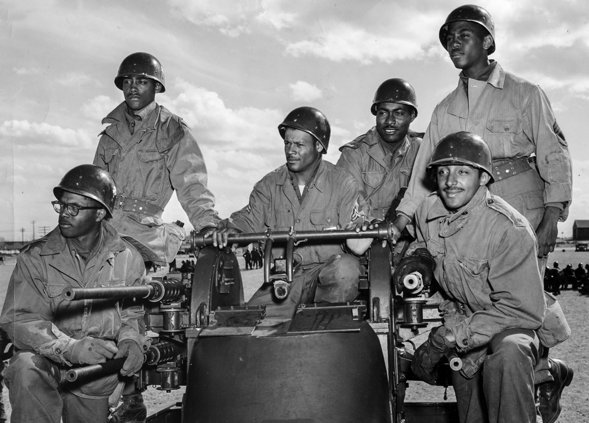 African-American Soldiers pose around guns.