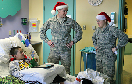 Staff Sgt. Logan Fuller (left) and 1st Lt. Jordan Hickey of the 178th Fighter Wing deliver a gift to a patient at the Dayton Children's Medical Center 
