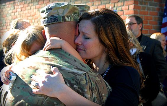 Staff Sgt. Rudy Harkless hugs his wife, Stacie, and daughter, Olivia, after stepping off the bus on Dec. 7, 2013, in Reynoldsburg, Ohio, before the welcome home ceremony for Advisor Team 1 after its deployment to Afghanistan. 