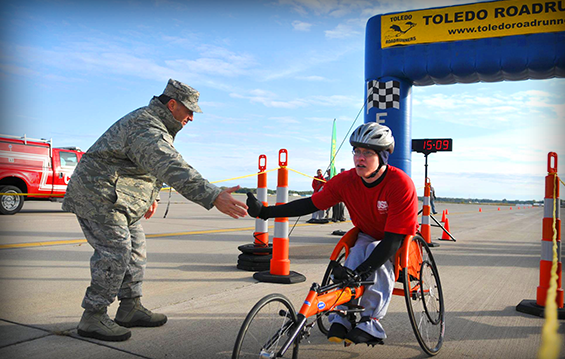 Col. Craig "Bluto" Baker, 180th Fighter Wing commander, congratulates Robert Burns as he crosses the finish line first in the "I Believe I Can Fly 5K" .