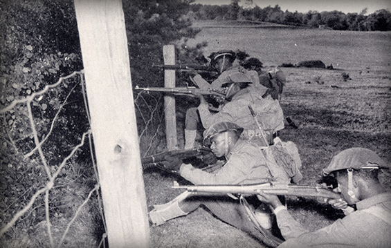 Company G Soldiers fire rifles from a camouflaged position during training at Fort Dix, N.J. in 1941.
