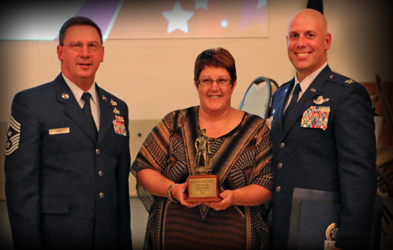 Chief Master Sgt. Thomas Jones (left) and Col. Gary McCue (right), command chief and commander of the 179th Airlift Wing, respectively, present the Minuteman Award to Vivian Winters.