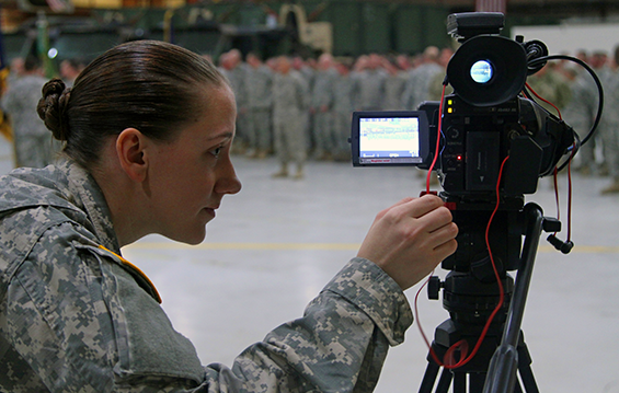 Spc. Hannah K. Selinsky, a public affairs broadcast specialist with the 196th Mobile Public Affairs Detachment checks her camera settings prior to a brigade change of command ceremony.