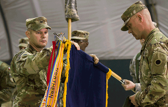 Col. Cory Lusk (left), commander of the 37th Infantry Brigade Combat Team, and 37th IBCT Command Sgt. Maj. Jeffrey Schuster unfurl the unit colors during a transfer of authority ceremony.