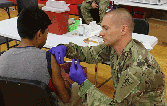 Capt. James Daugherty administers an immunization vaccine to a young man.