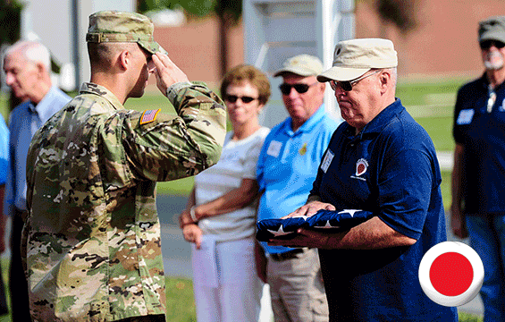Sgt. Scot Nabors of Company D, 1st Battalion, 148th Infantry Regiment salutes the flag after presenting it to retired Command Sgt. Maj. Craig Huffman.