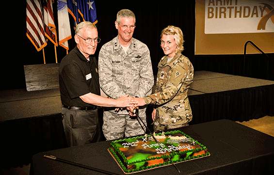 Maj. Gen. Mark E. Bartman is assisted by retired Col. John Enyrt  and Spc. Susan Higgenbotham in making the first cut in the cake.
