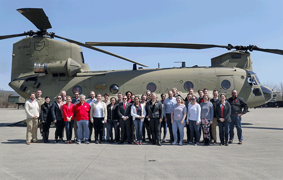 Group stand in front of Chinook helicopter.