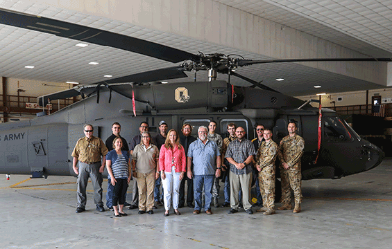 Group photo in front of a blackhawk helicopter inside hangar.